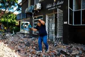 Colombia earthquake aftermath showing a damaged building, shattered windows, and debris covering the street outside a storefront.