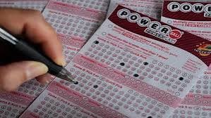 Powerball lottery tickets with numbered plays being marked by hand, representing the lottery Powerball jackpot.