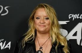 Lucy Davis posing at a BBC America and BAFTA/LA event, wearing a colorful dress and smiling at the camera.