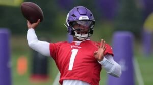Kyler Murray throwing a football during Minnesota Vikings practice while wearing a purple helmet and red practice jersey.